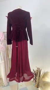 Detailed back view of a vintage burgundy velvet jacket with lace-up detail and pleated skirt