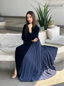 Detail view of a navy blue velvet robe with a pleated patchwork skirt on a model.