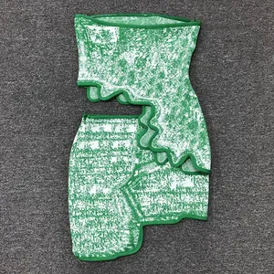 Close-up detail of green jacquard two-piece set featuring irregular wavy hemlines