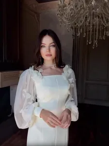 Elegante abito bianco con maniche a sbuffo trasparenti e applicazioni floreali 2025