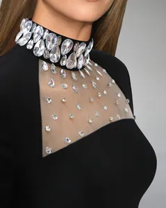 Dettaglio di un elegante abito nero con colletto decorato di cristalli e scollo in rete