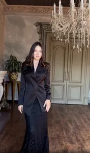Full-length model view of an elegant black blazer and skirt set in a classic room