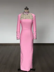 Elegante abito da sera rosa a maniche lunghe con un raffinato scollo in rete ornato di strass