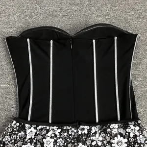 Detailed view of a black strapless corset dress with white sequin floral patterns