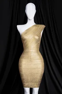Macro view of luxurious gold foil bandage fabric on a stylish one-shoulder bodycon dress