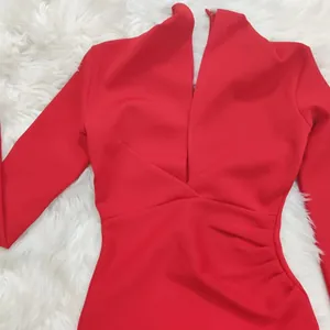 Close-up detail of a red long sleeve bandage dress with a deep V-neck and ruched side.