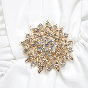Detail of a gold sunburst brooch with clear rhinestones on white pleated dress fabric