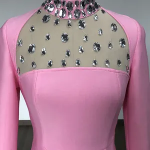 Dettaglio di un abito rosa a maniche lunghe con scollatura in mesh decorata con strass.