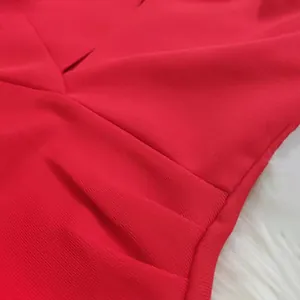 Close-up detail of vibrant red bandage dress showing V-neck pleats and fine fabric texture