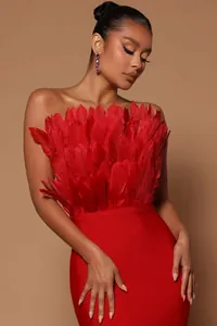Detailed view of elegant red strapless bandage dress with ostrich feather bodice decor.