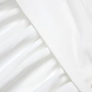 Macro view of white French-style dress fabric texture showing pleats and fine seams