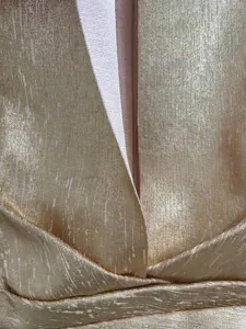 Detail view showing the shimmering champagne gold textured fabric of a deep V-neck dress