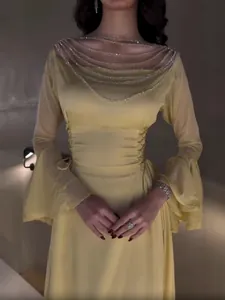 Elegante abito da sera giallo a maniche lunghe con scollo a catena e vita a pieghe