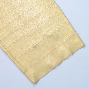 Macro detail showing the luxurious gold bronzed fabric texture on a stylish bandage dress