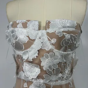 Detailed macro view of delicate white floral embroidery on a nude mesh strapless gown