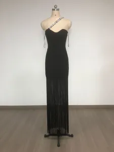 Detail view of a black bandage dress featuring a rhinestone chain strap and long fringe hem