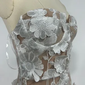 Detailed macro view of intricate white 3D floral embroidery on a nude strapless banquet gown