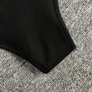 Macro view showing the fine stitching and premium black fabric texture of this bodysuit.