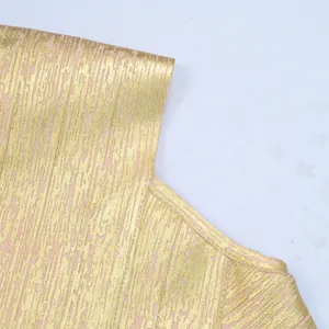 Detailed macro view of the shimmering gold bronzing fabric on a sexy pink bandage dress