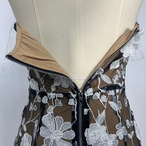 Back zipper detail of a strapless mesh dress with white floral embroidery and tan lining