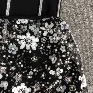 Close-up detail of white flower sequins and intricate beadwork on black mesh gala dress.