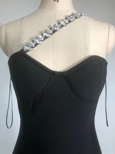 Close-up of sparkling rhinestone strap detail on a black one-shoulder bandage dress