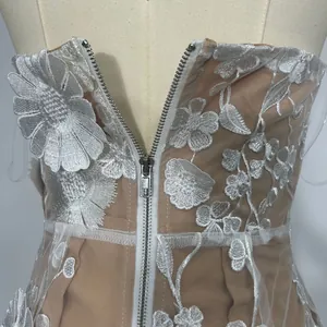 Detail view of 3D white floral lace embroidery on a champagne strapless evening gown.