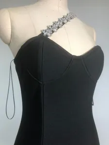 Detailed view of the sparkling rhinestone chain on an elegant black one-shoulder bandage dress