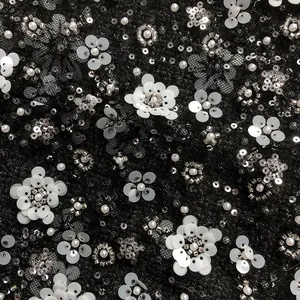 Detailed macro view of black lace fabric with white sequins, silver beads, and pearls