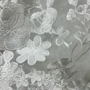 Macro view of delicate white stereoscopic flower embroidery on high-end lace dress fabric