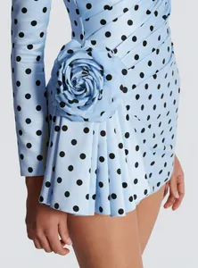 Close-up of light blue polka dot dress featuring a 3D flower and pleated detail.