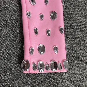 Dettaglio macro di strass sfaccettati cuciti sul tessuto rosa elasticizzato della manica