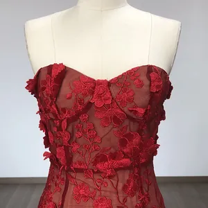 Detailed view of red lace fabric and 3D floral embroidery on an elegant strapless dress.
