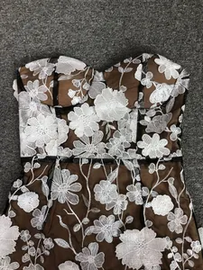 Close-up detail showing exquisite white floral embroidery on a brown strapless mesh dress