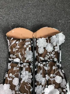 Close-up of white floral embroidery and zipper detail on mesh evening dress