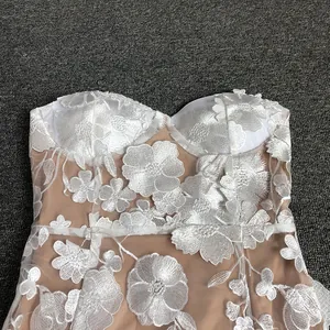 Detailed view of white 3D floral lace embroidery on elegant evening dress fabric