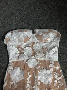 Macro view of intricate white floral embroidery on a nude strapless evening banquet dress