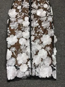 Intricate white floral embroidery detail on a brown mesh evening dress featuring a zipper