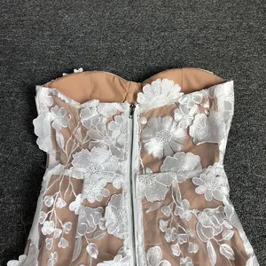 Detailed close-up of back zipper and 3D floral lace embroidery on white strapless dress