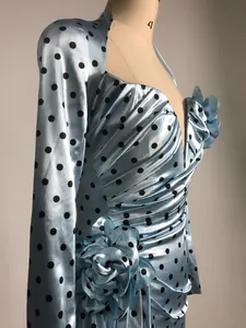 Close-up of elegant light blue polka dot dress with deep V-neck and 3D floral detail