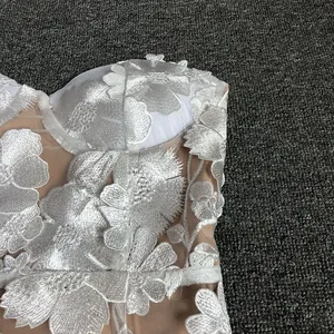Close-up detail of white 3D floral lace embroidery on elegant mesh evening dress fabric