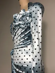Detail view of the 3D flower and pleated texture on blue polka dot satin evening dress