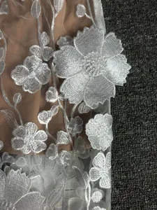 Close-up of intricate white 3D floral embroidery on elegant mesh evening dress