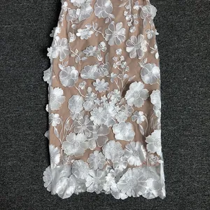 Detailed view of exquisite white 3D floral lace embroidery on a nude mesh evening dress