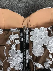 Close-up detail showing intricate white floral embroidery and zipper on black mesh party dress