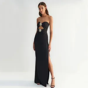 Elegant black strapless maxi dress with gold stud details and sun-shaped metal accents.