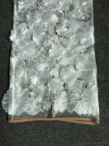Close-up detail of white 3D floral embroidery on sheer mesh with elegant tan trim piping