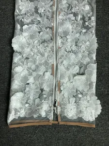 Detailed view of white 3D floral lace embroidery on an elegant evening gown with zipper.