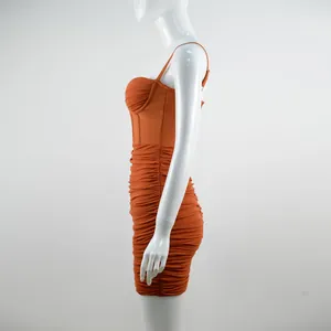 Dettaglio laterale di un abito aderente arancione con ruches e corpetto a corsetto