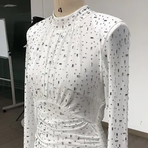 Close-up of white mesh mini dress featuring intricate silver rhinestone embellishments